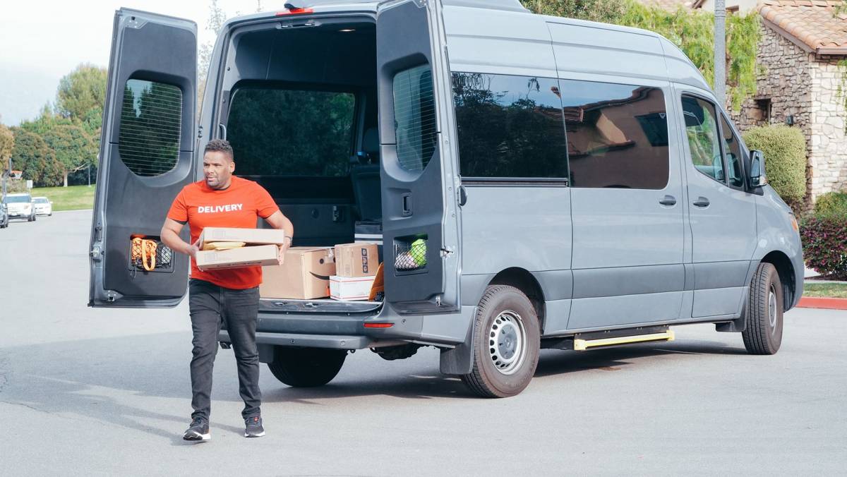 Courier delivering packages from a delivery van in a suburban neighborhood