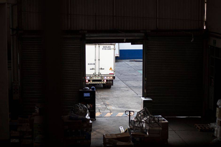 Delivery truck at a dimly lit warehouse loading dock surrounded by packages