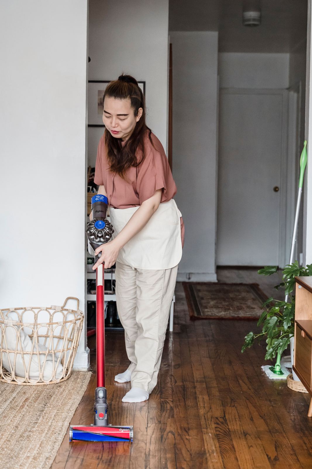 Woman cleaning a wooden floor with a cordless Dyson stick vacuum
