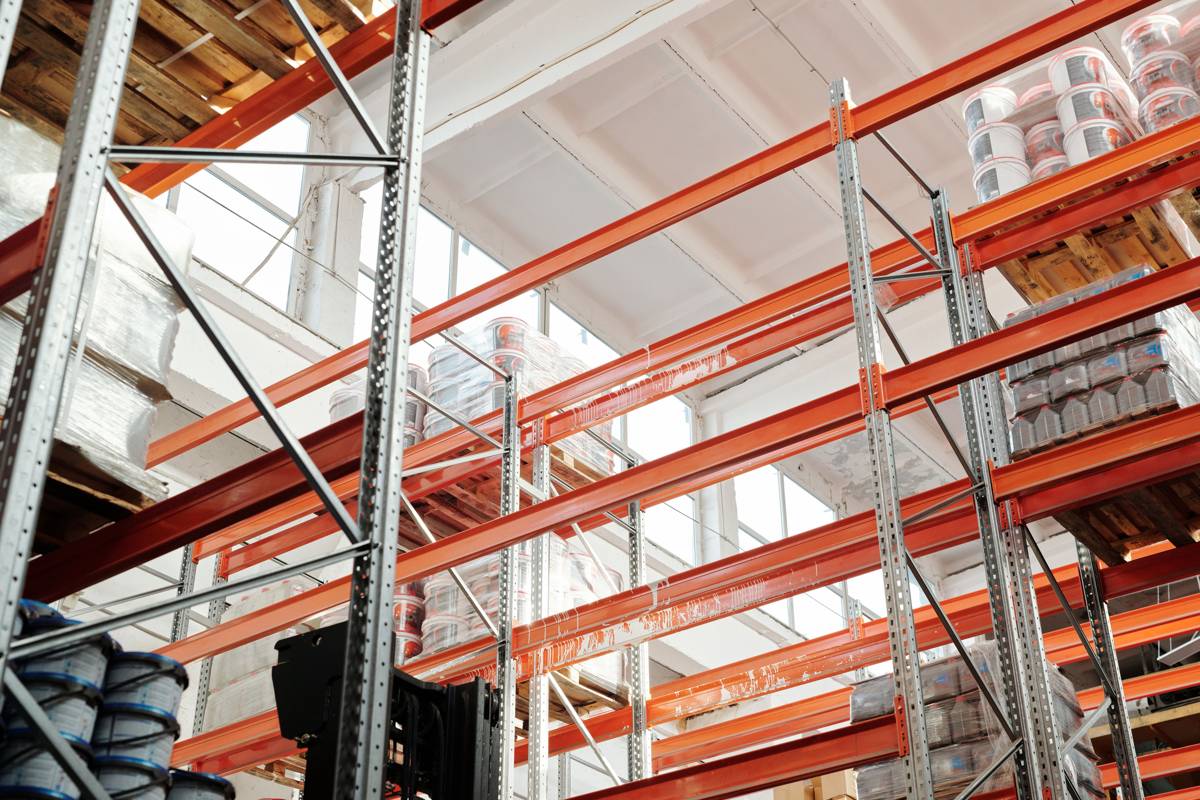 Pallet racking holding wrapped stock and containers in a bright warehouse.