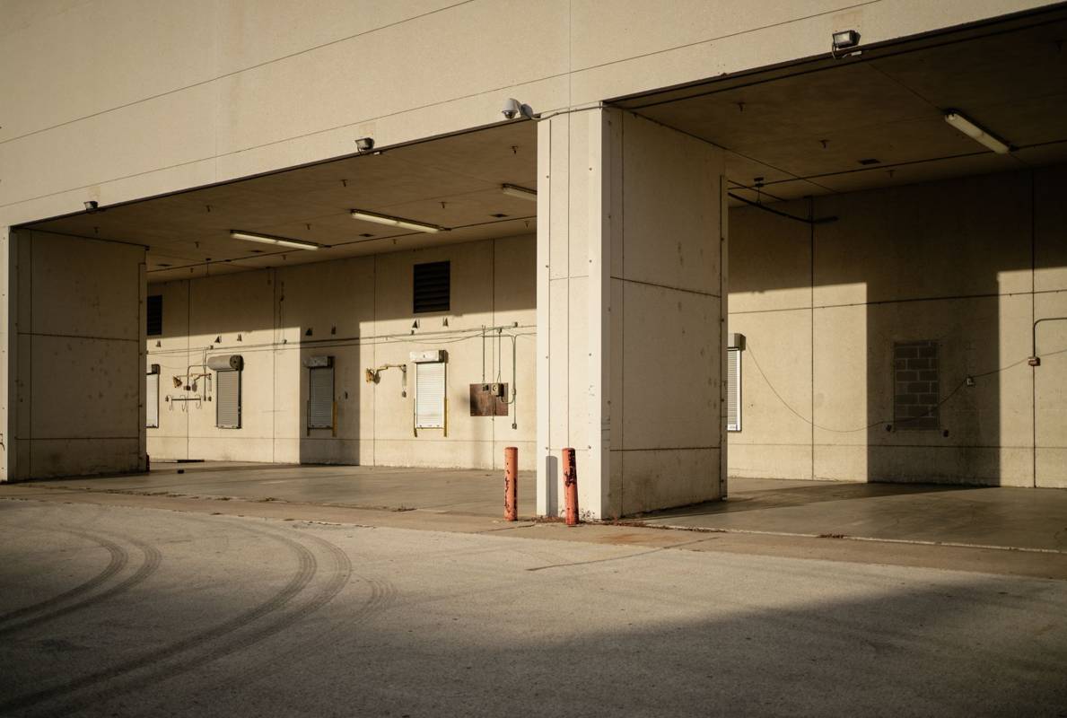Empty industrial loading dock with concrete pillars and closed roll-up doors
